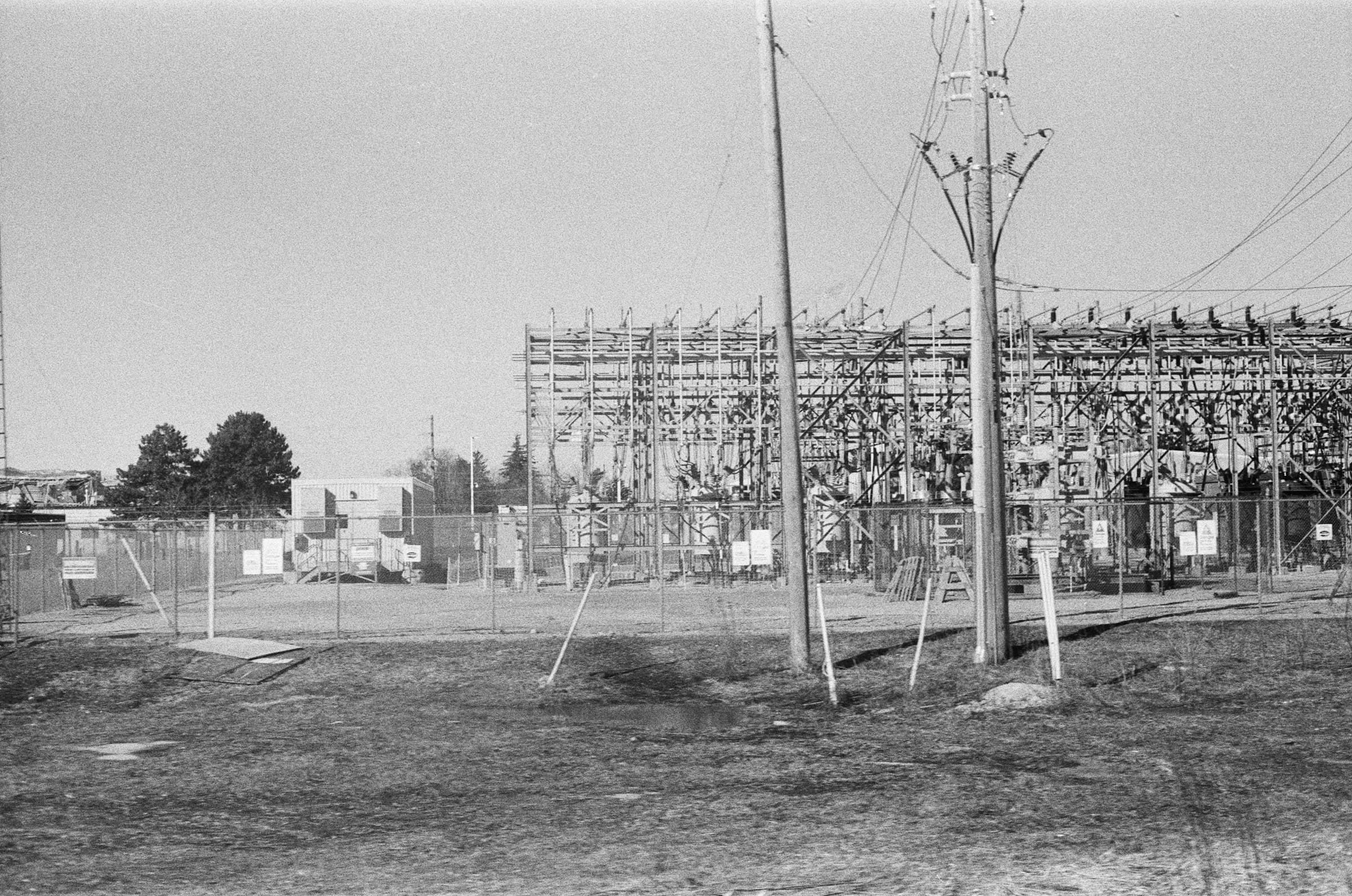 Substation steelwork, busbars and disconnectors standing behind a perimeter fence.